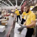 A man placing a shipping box on a conveyor belt