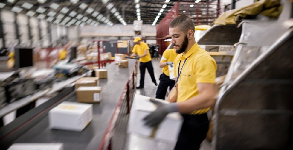 A man placing a shipping box on a conveyor belt