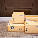 A stack of delivered packages sitting on a porch.