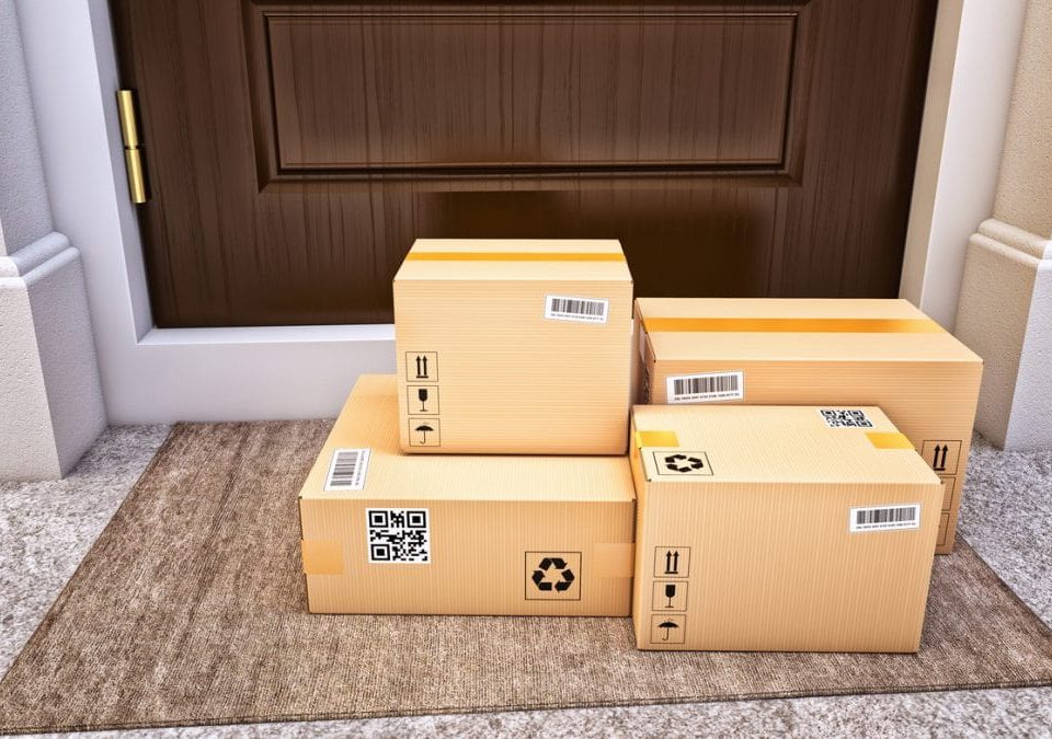 A stack of delivered packages sitting on a porch.