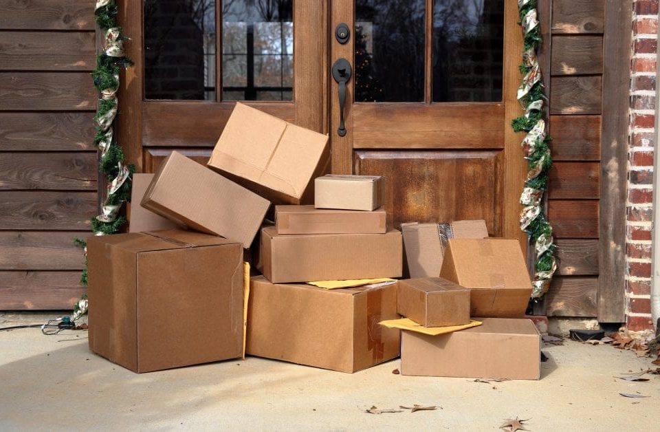 Multiple boxes and packages sitting on a porch.