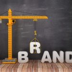 A crane lifting the "B" in "Brand"
