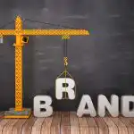 A crane lifting the "B" in "Brand"