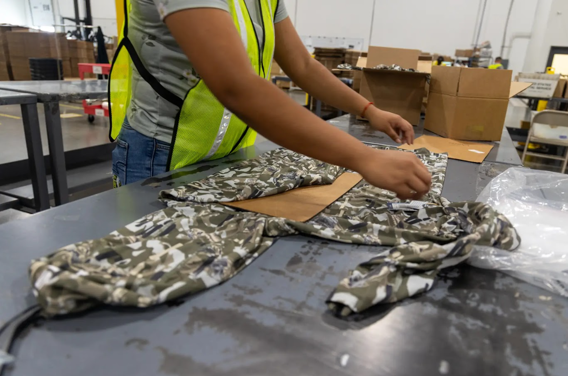 worker folding sweatshirt at apparel fulfillment company